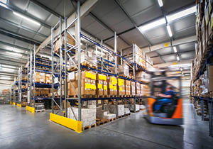 warehouse interior wit blurred forklift and worker in logistic center