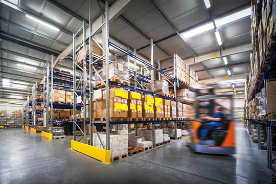 warehouse interior wit blurred forklift and worker in logistic center